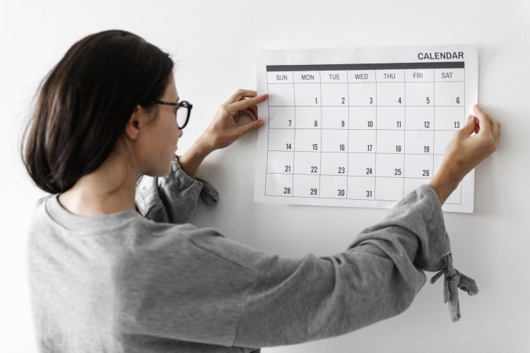 foto de mulher verificando um calendário pendurado na parede